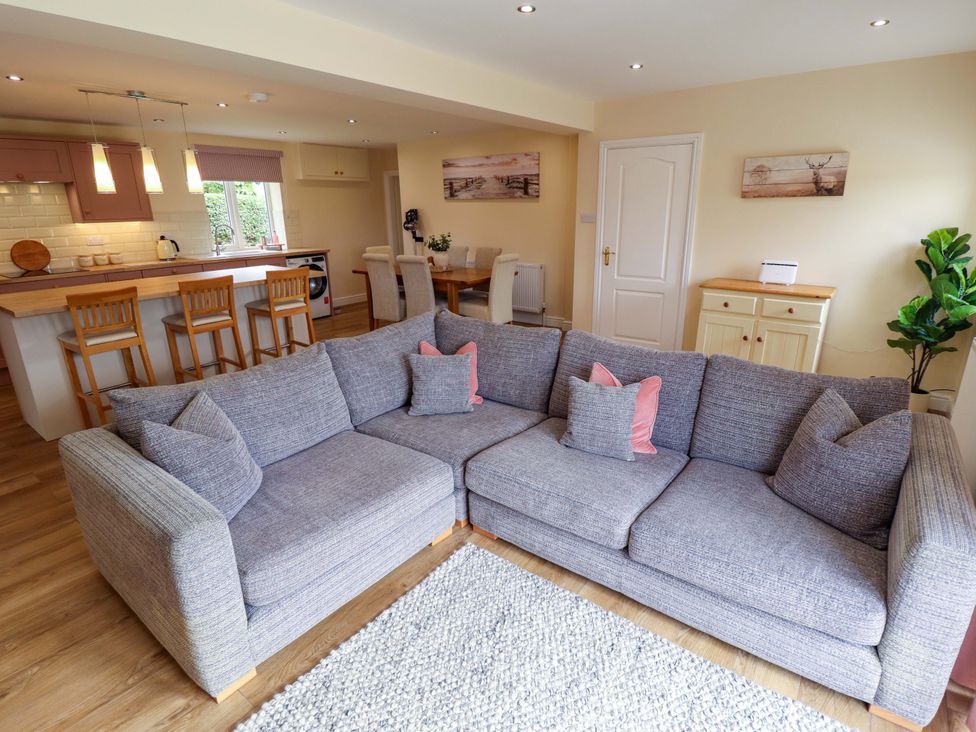 A living room with a sofa and dining area at Denholme in Hogsthorpe