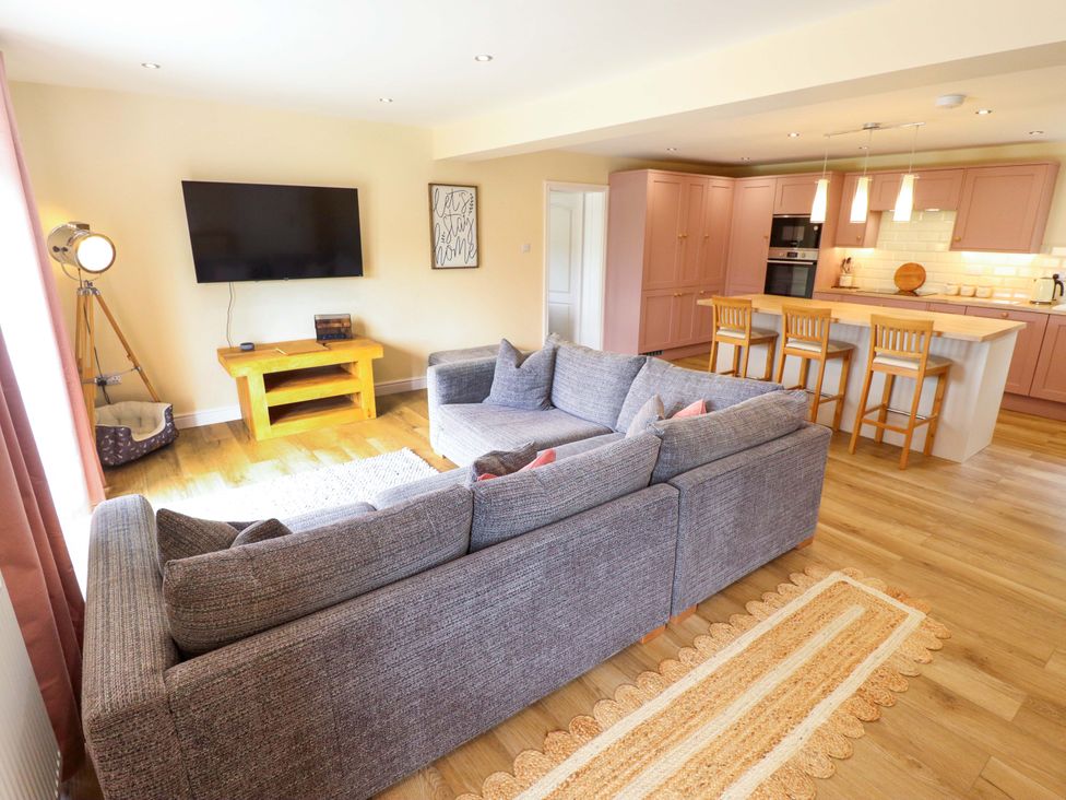A living room with a television and a sofa at Denholme in Hogsthorpe