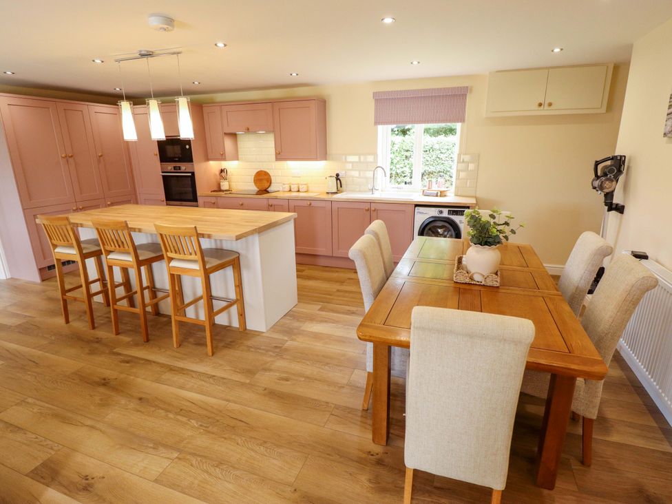 A kitchen with an island and dining table at Denholme in Hogsthorpe