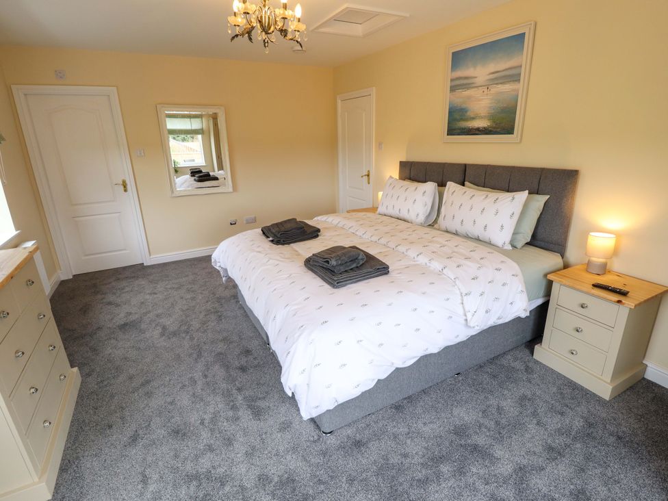 A bedroom with a bed and nightstand at Denholme in Hogsthorpe