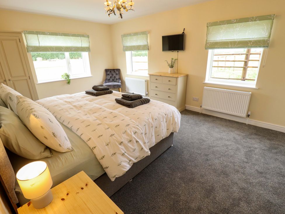 A bedroom with a bed and nightstand at Denholme in Hogsthorpe