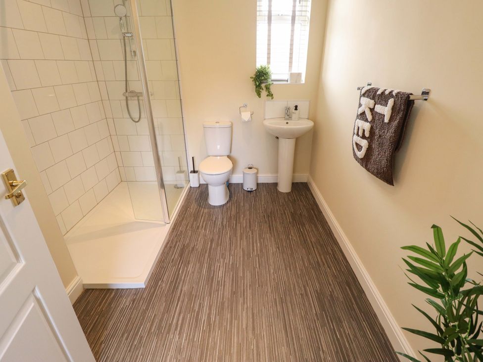 A bathroom with a shower, toilet, sink, and towel at Denholme in Hogsthorpe