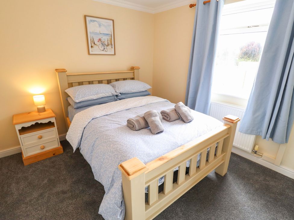 A bedroom with a bed and bedside table at Denholme in Hogsthorpe