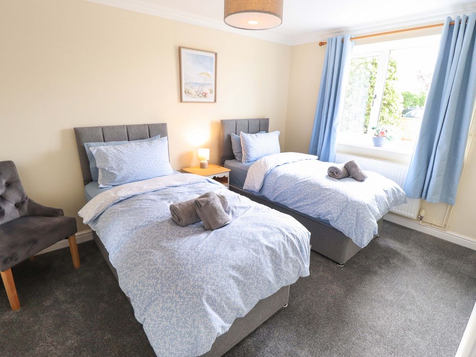 A bedroom with two beds and a chair at Denholme in Hogsthorpe