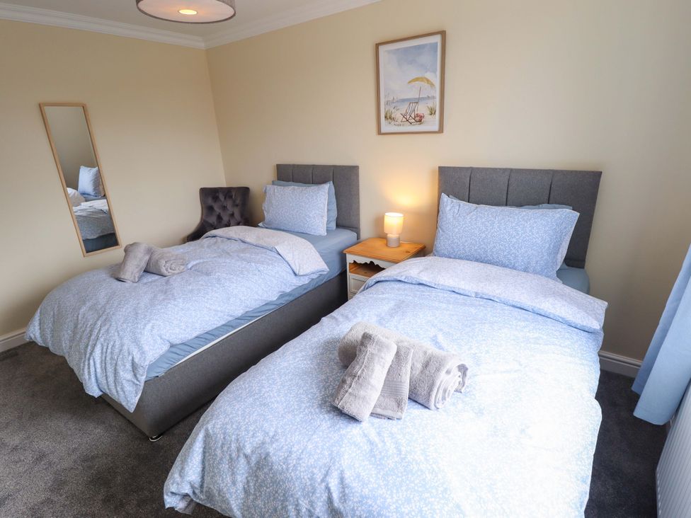 A bedroom with twin beds and a bedside table at Denholme in Hogsthorpe