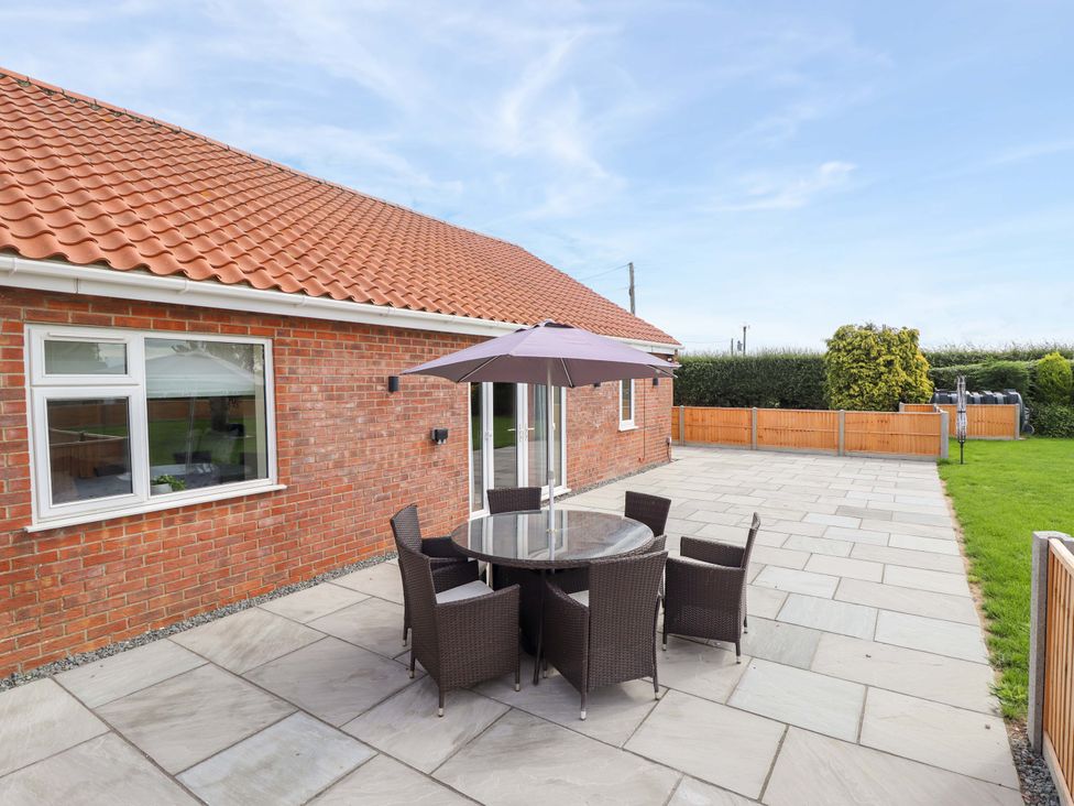 A patio area with a table and chairs at Denholme in Hogsthorpe