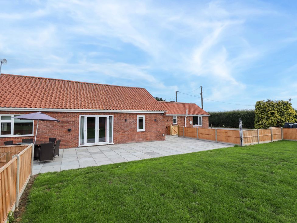 An outdoor area with a patio and grass at Denholme in Hogsthorpe