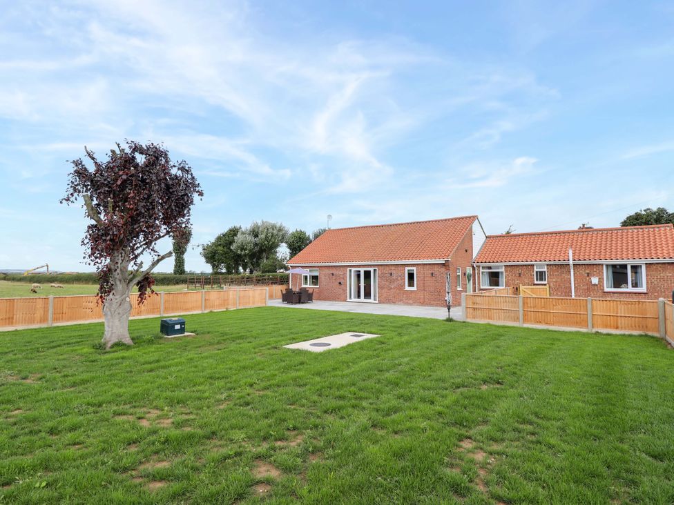 A garden with a house and tree at Denholme in Hogsthorpe