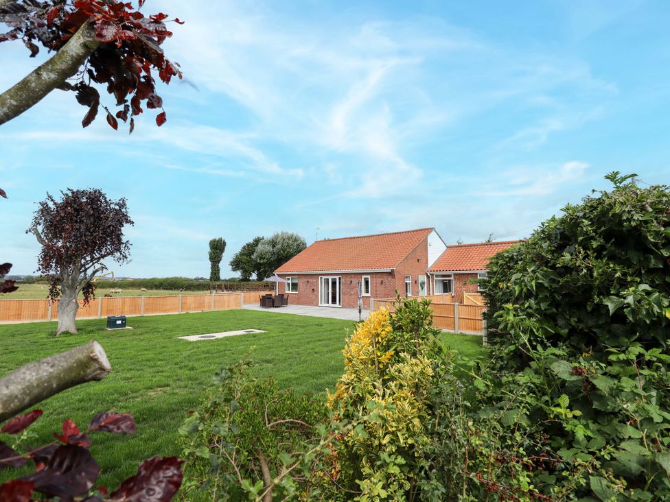 A house with a lawn and trees at Denholme in Hogsthorpe