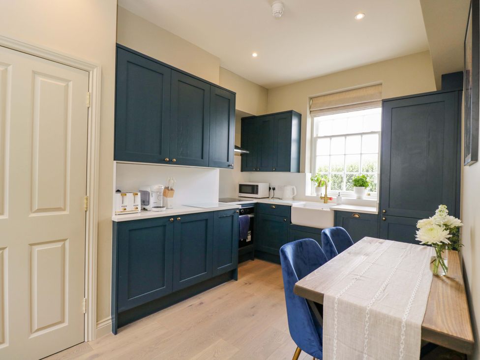 A kitchen with blue cabinets and a dining table at Beech in Newbury