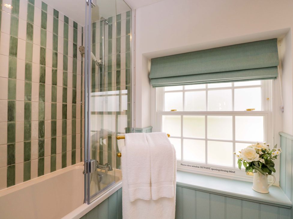 A bathroom with a bathtub and shower next to a window at Beech, Newbury
