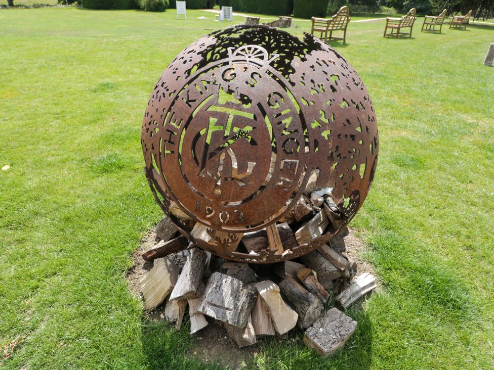 A metal orb sculpture with wood base and benches at Beech in Newbury