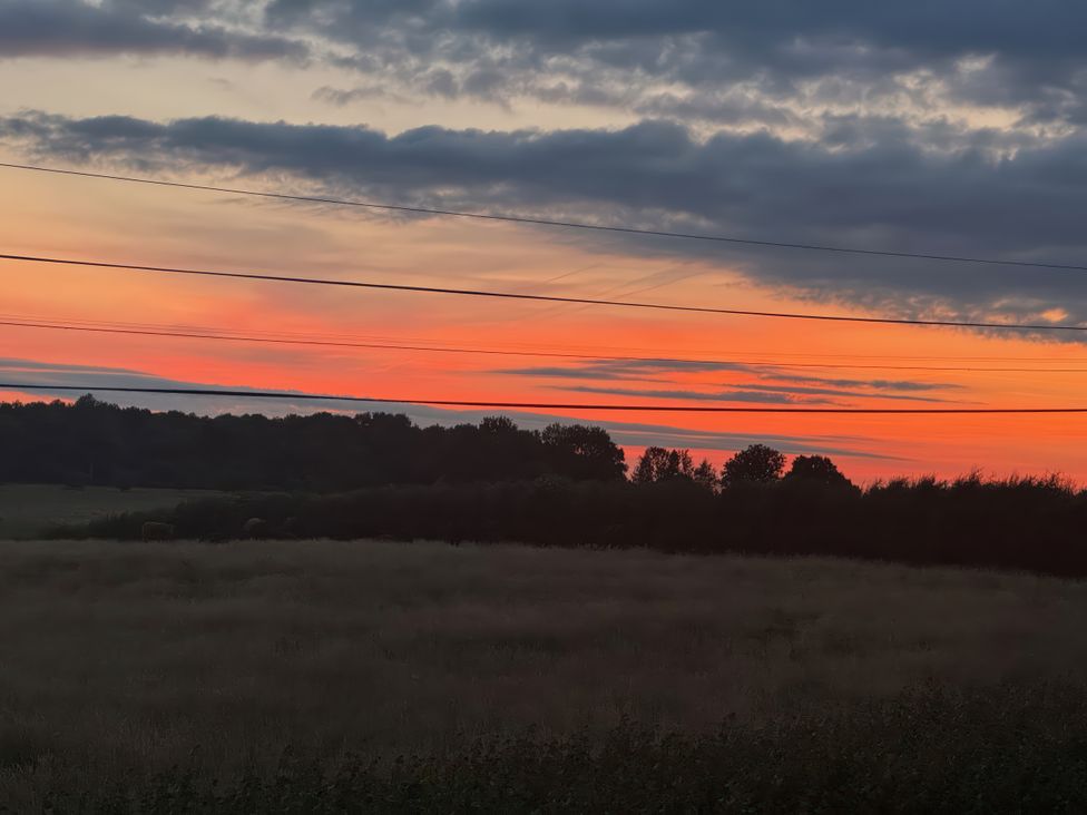 A sunset with clouds over a field and trees at Beech in Elcot near Kintbury