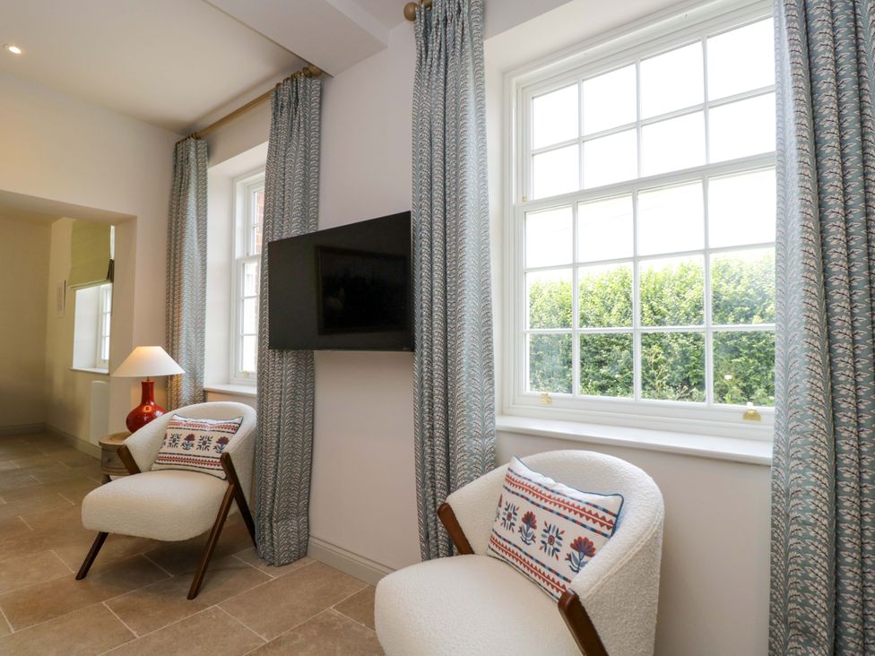 A living room with a television and chairs at Hazel in Elcot near Kintbury