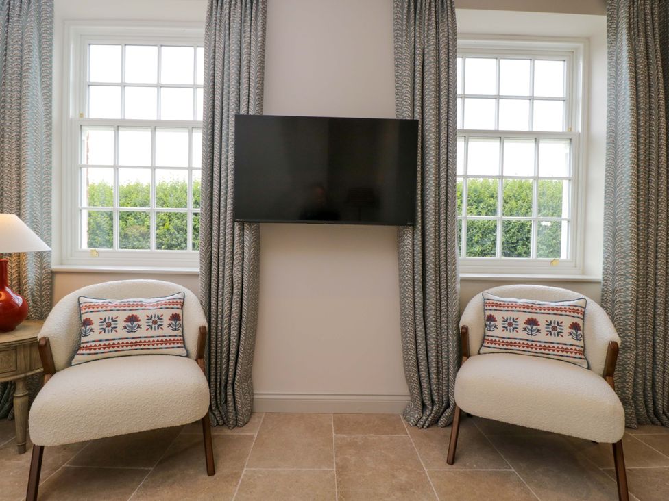 A living room with a television and two armchairs at Hazel in Elcot near Kintbury