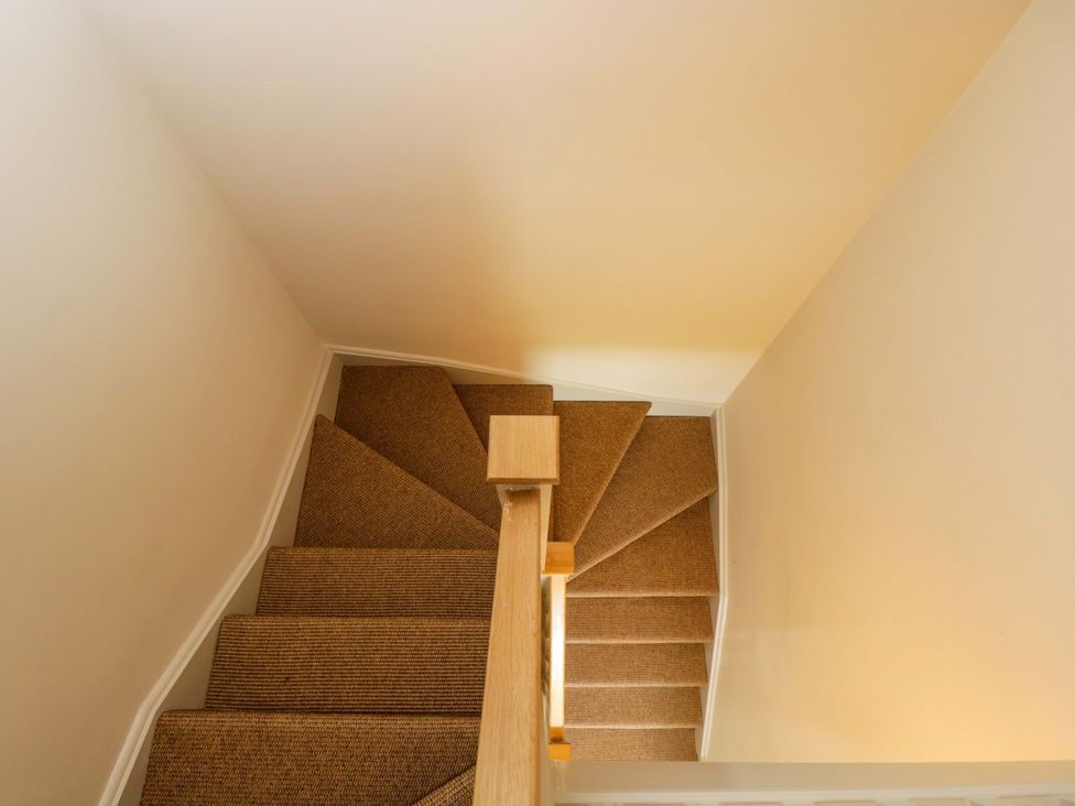A staircase with carpet and a wooden handrail at Hazel in Elcot near Kintbury