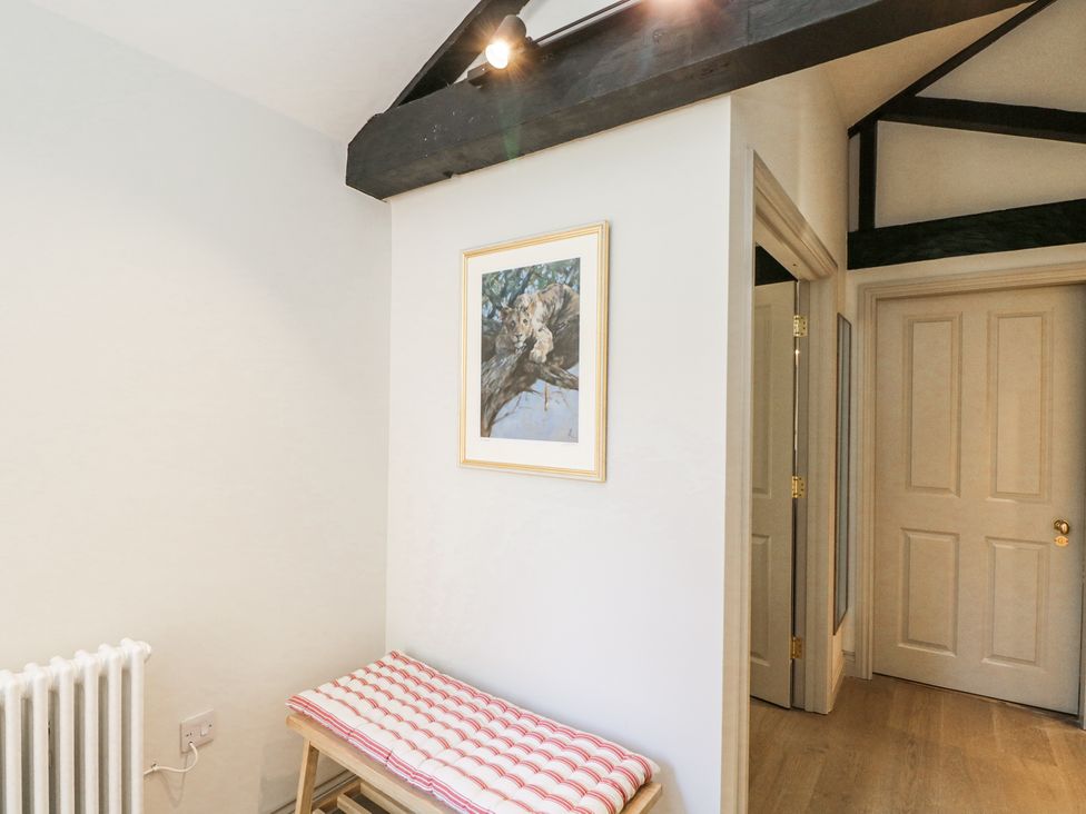A hallway with a wooden bench with a cushion radiator and framed picture on the wall at Cedar in Elcot near Newbury
