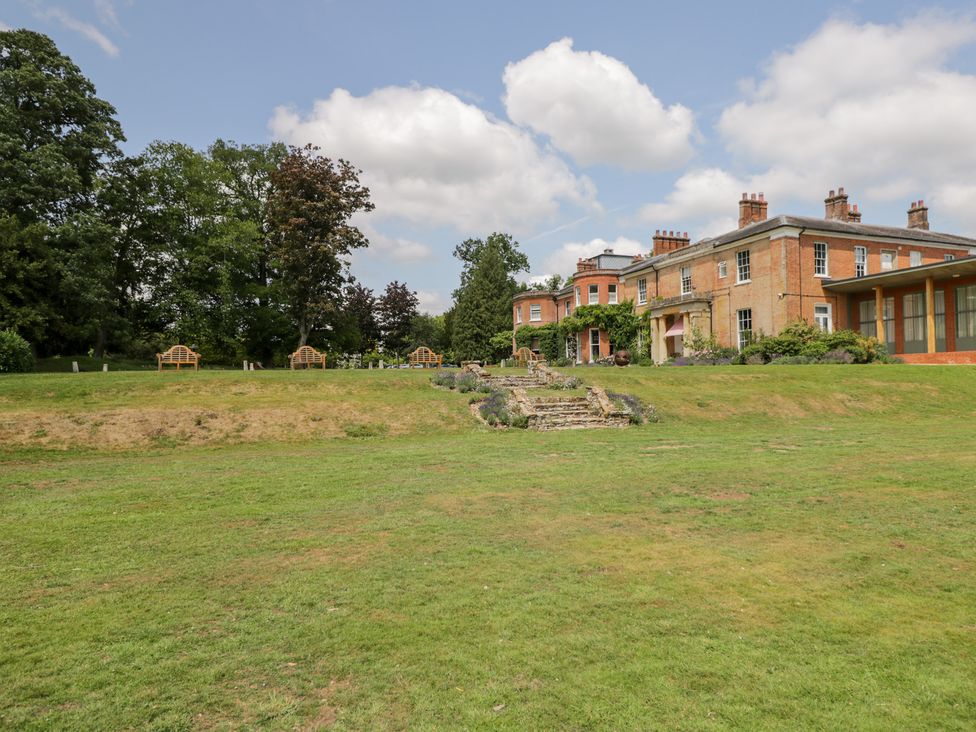 A garden with benches and a house in the background at Cedar Elcot near Newbury