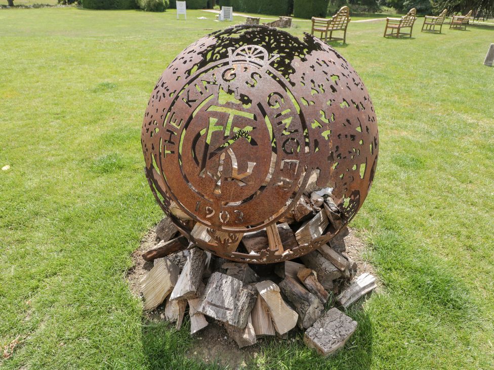 A metal sculpture on logs in a grassy area at Oak Elcot near Newbury
