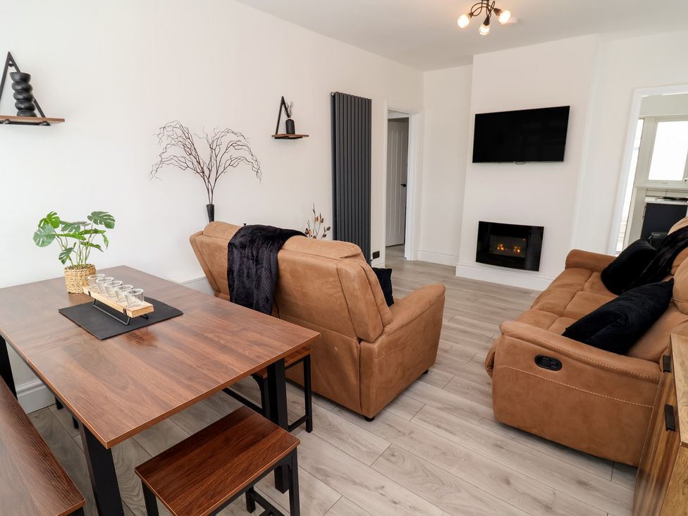 A living room with a sofa and dining table at Driftwood in Rhyl