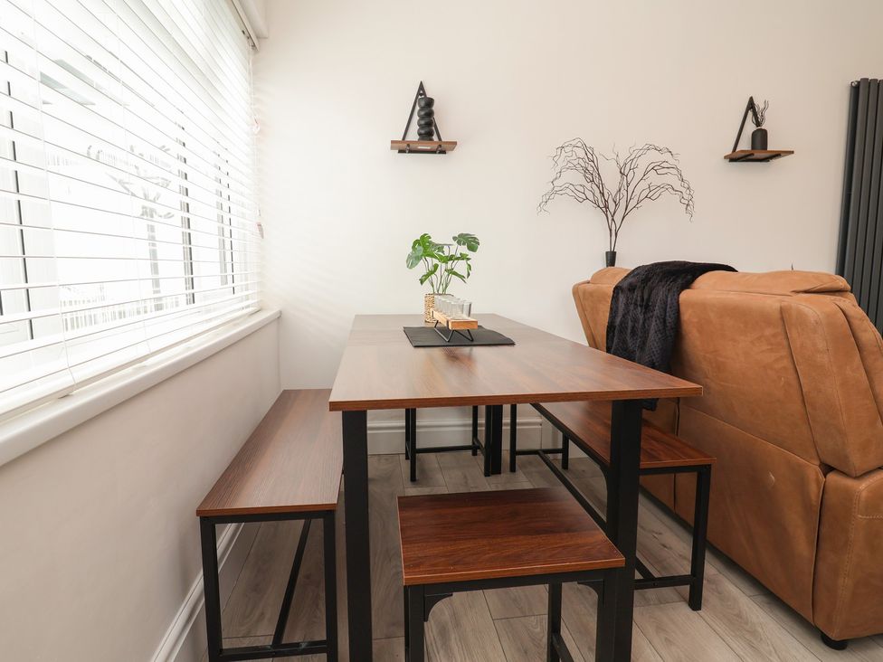 A dining room with a table and benches at Driftwood Rhyl