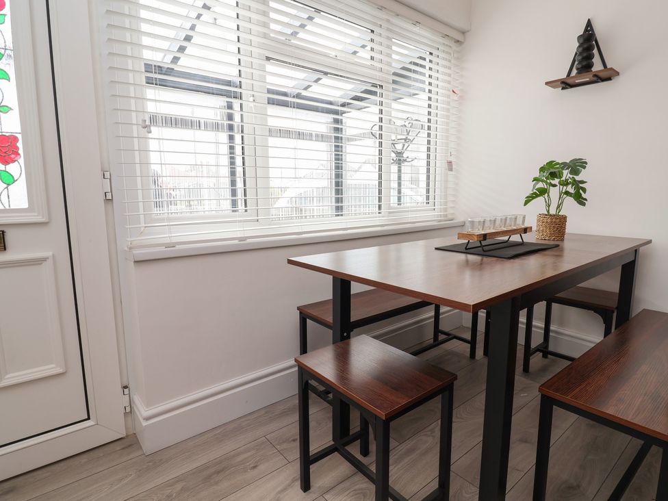 A dining room with a table and stools at Driftwood in Rhyl