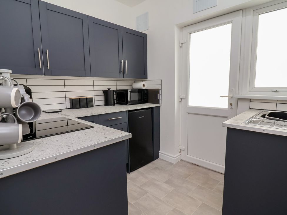 A kitchen with cabinets and appliances including a microwave and coffee machine at Driftwood in Rhyl