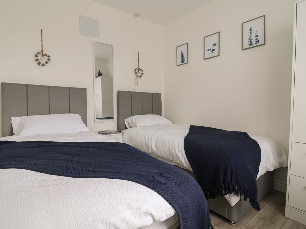 A bedroom with two beds and a mirror at Driftwood in Rhyl