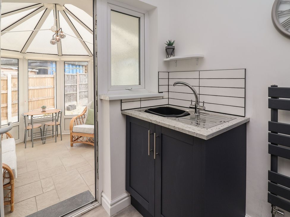A kitchen area with a sink and cabinets at Driftwood in Rhyl