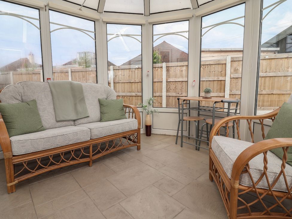 A conservatory with a sofa and a table at Driftwood in Rhyl