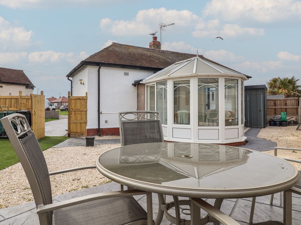 A garden with a table and chairs near a conservatory at Driftwood in Rhyl