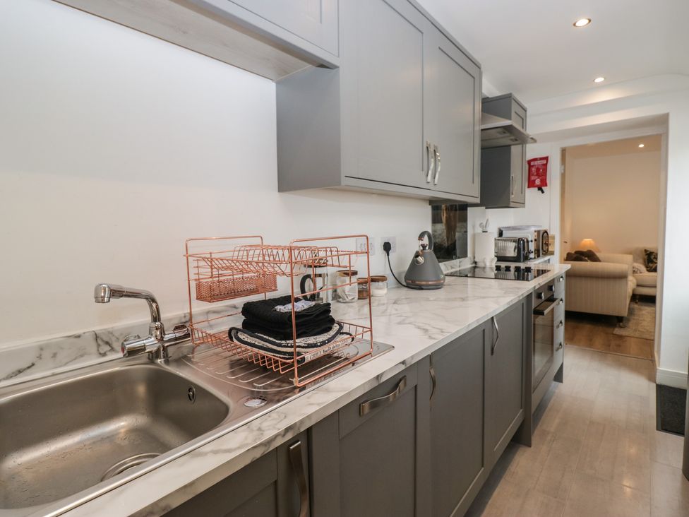 A kitchen with a sink, dish rack, and appliances at Highfield Cottage in Windermere