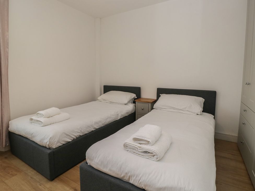 A bedroom with twin beds and a bedside table at Highfield Cottage in Windermere