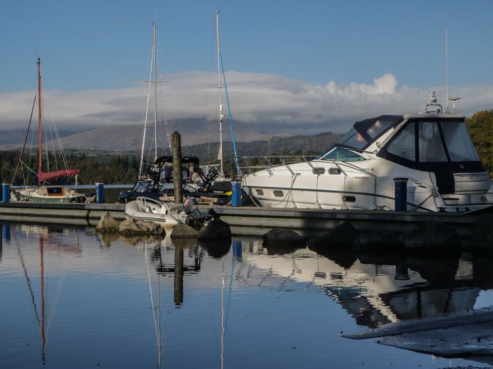 A dock with boats and mountains visible near the water at Highfield Cottage in Windermere