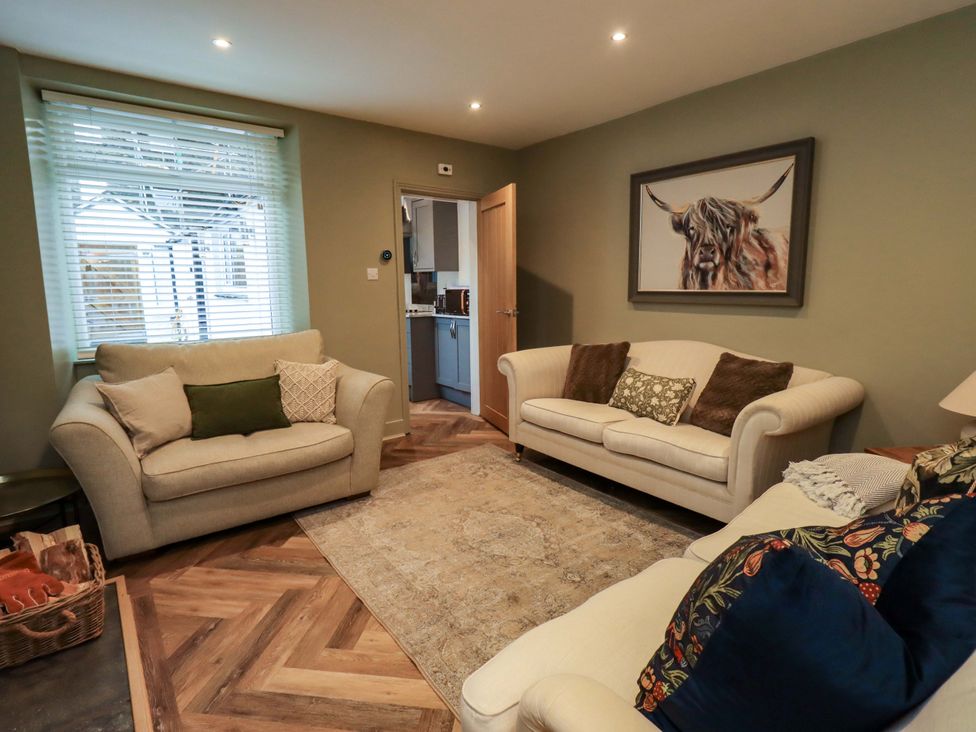 A living room with sofas and a painting at Highfield Cottage in Windermere