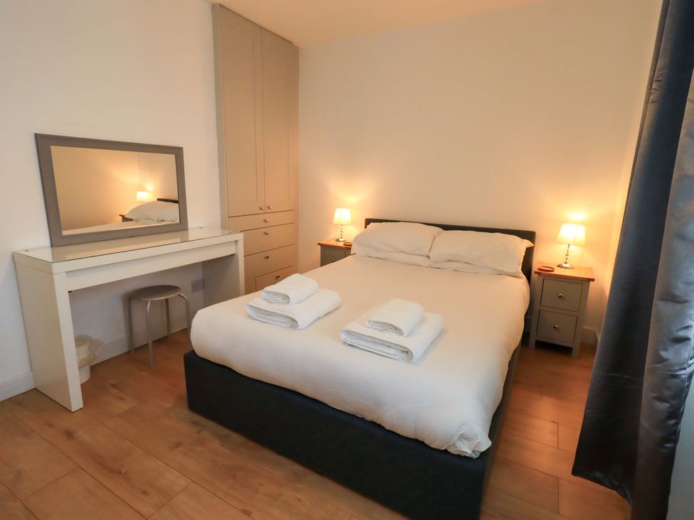 A bedroom with a bed and mirror at Highfield Cottage in Windermere