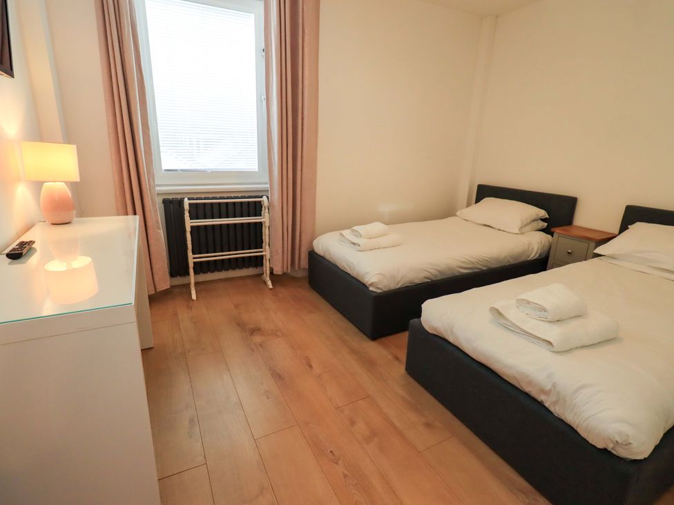 A bedroom with two beds and a window at Highfield Cottage in Windermere