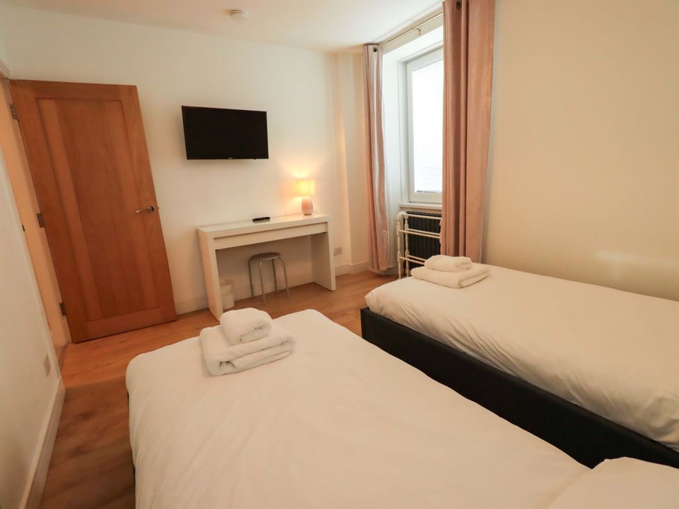 A bedroom with two beds and a desk at Highfield Cottage in Windermere