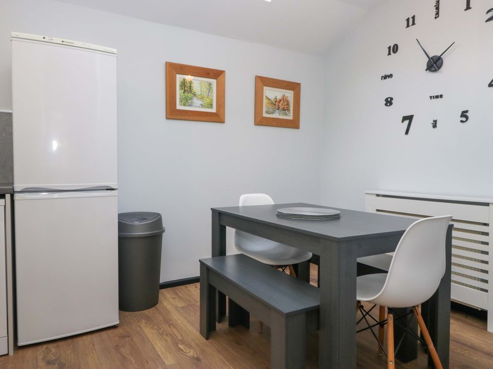 A kitchen with refrigerator, dining table and chairs at Havelock Hideaway in Windermere