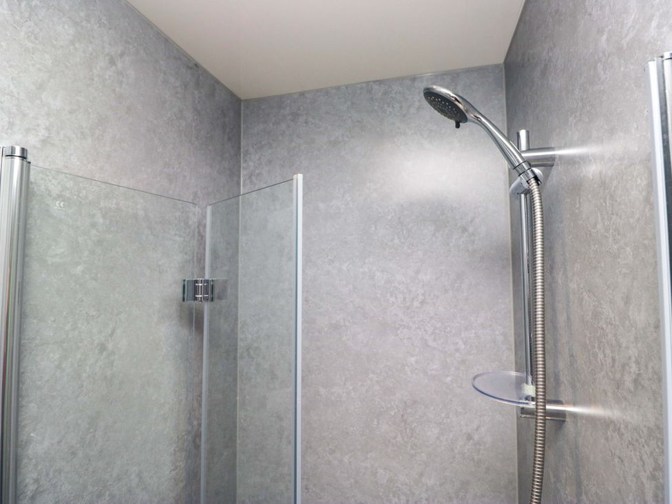 A shower area with glass partitions and showerhead at Havelock Hideaway in Windermere