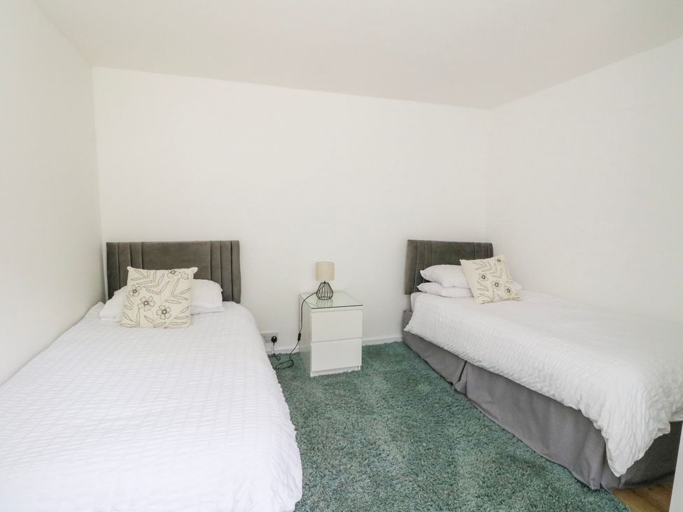 A bedroom with two beds and a nightstand at 3 Whin Bank, Clachan-Seil near Balvicar, Isle Of Seil