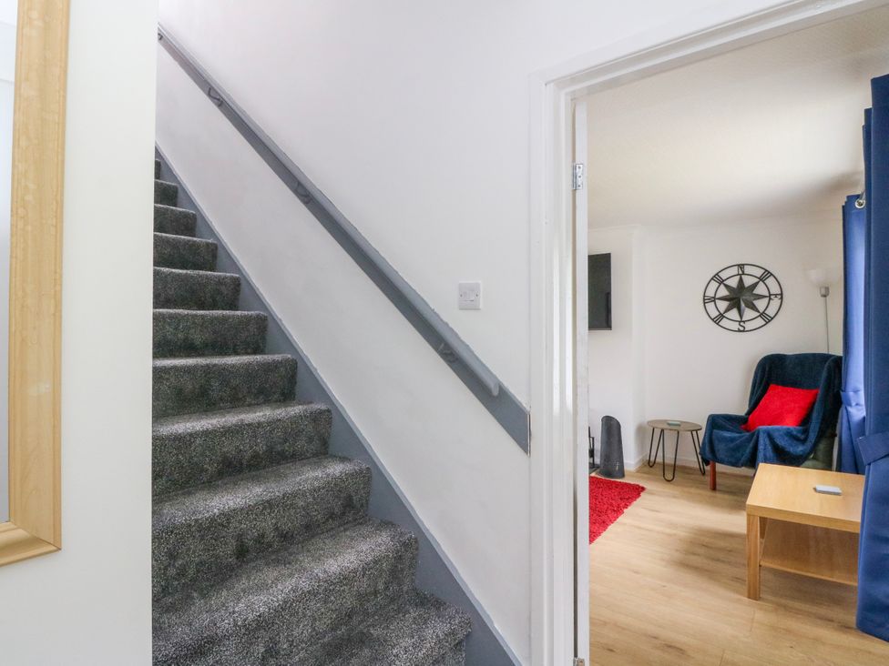 A hallway with stairs and a view into a sitting room at 3 Whin Bank Clachan-Seil near Balvicar, Isle Of Seil