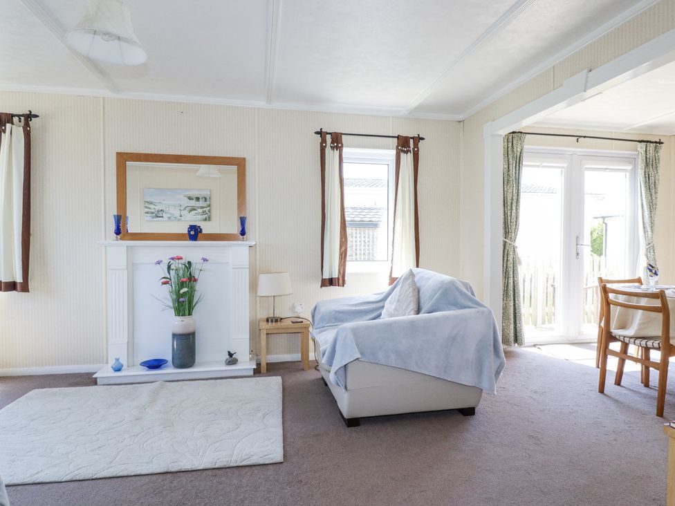 A living room with a sofa and fireplace at Lazy Days in St Merryn