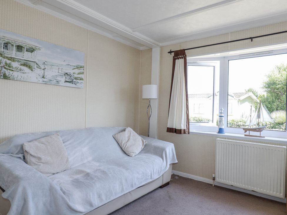 A living room with a sofa and window at Lazy Days in St Merryn