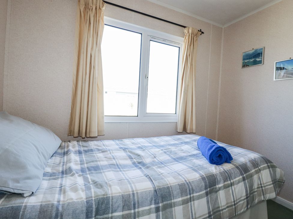 A bedroom with a bed and a window at Lazy Days in St Merryn