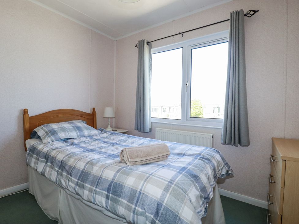 A bedroom with a bed, lamp, and window at Lazy Days in St Merryn