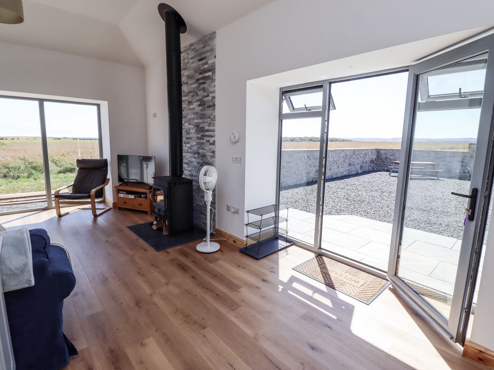 A living room with a sofa and wood stove at West Burton Hemmel in Bamburgh