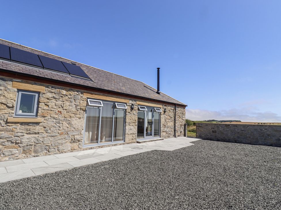 An exterior view of a stone house with solar panels at West Burton Hemmel in Bamburgh