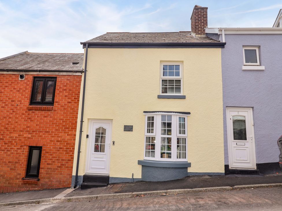 A house with a yellow facade and white windows at Lilly's Cottage in Dawlish