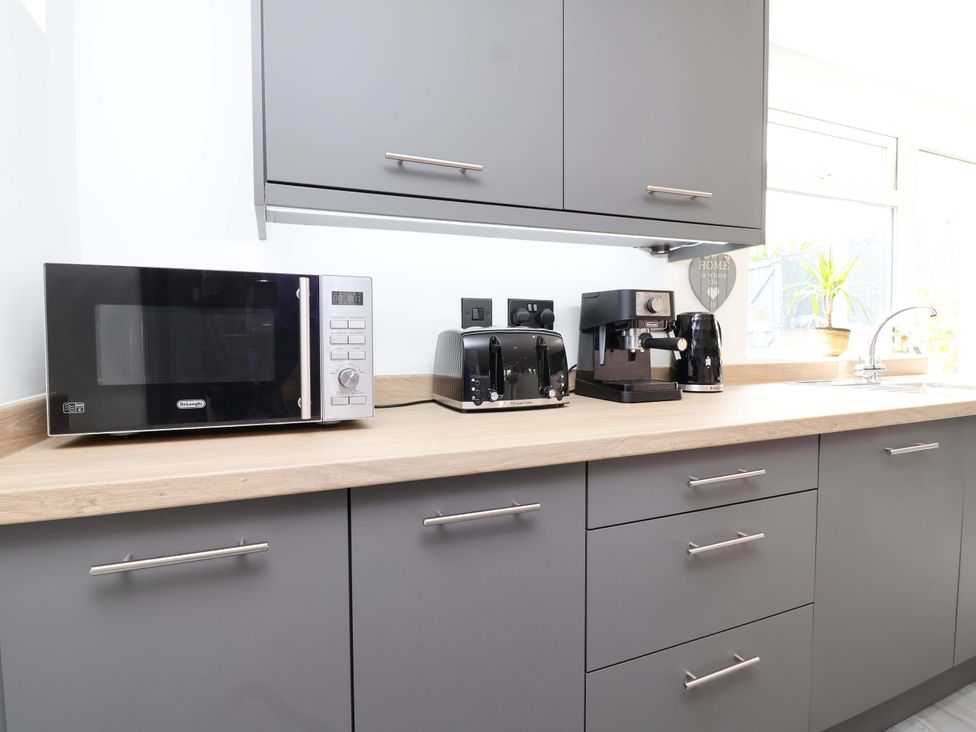 A kitchen with appliances and cabinetry at Lilly's Cottage Dawlish
